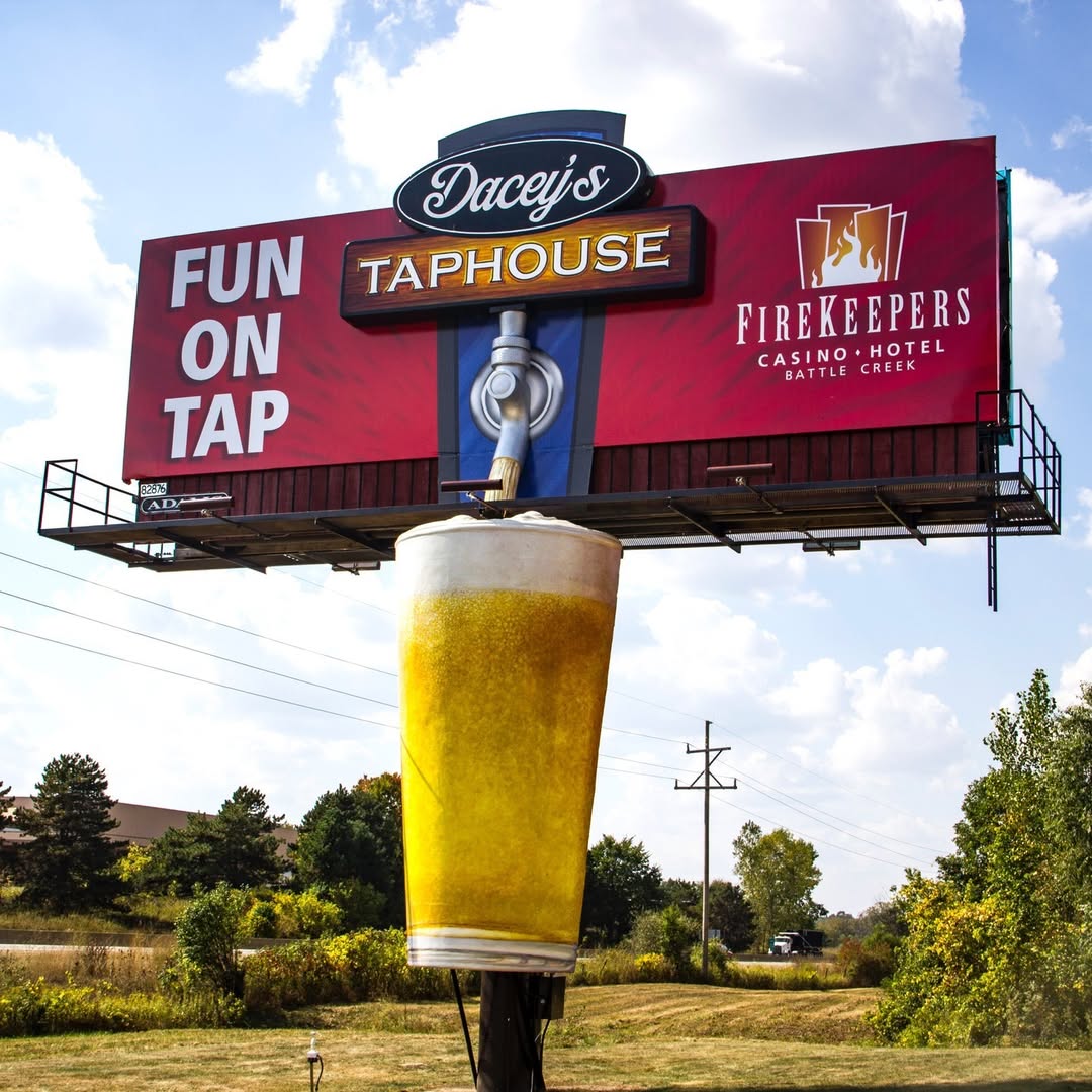 Dacy's TapHouse billboard featuring a giant 3D beer tap and mug of beer.